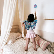 Kind mit Zauberstab und Flügel steht auf Bett: von DIY: Feenflügel & Zauberstab von Djeco