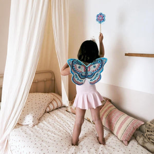 Kind mit Zauberstab und Flügel steht auf Bett: von DIY: Feenflügel & Zauberstab von Djeco