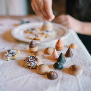 Bakes - handbemaltes Gebäck aus Holz von Grapat neben echtem Gebäck und Kind
