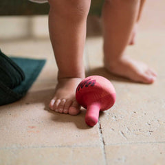 Chill Pink Bird von Grapat - Stehaufmännchen liegt am Boden neben Kinderfüßen