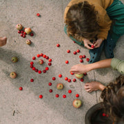Kinder spielen mit 36 Halbkugeln als Mandala-Set von Grapat in Rottönen