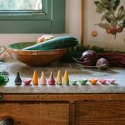 Veggies von Grapat - handbemaltes Holzgemüse liegt auf Arbeitsplatte neben echtem Gemüse