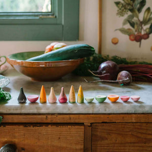 Veggies von Grapat - handbemaltes Holzgemüse liegt auf Arbeitsplatte neben echtem Gemüse