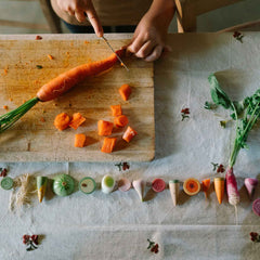 Kind schneidet Karotte, daneben liegt Veggies von Grapat - handbemaltes Holzgemüse