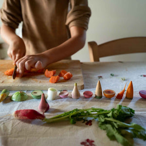 Kind schneidet Karotte, daneben liegt Veggies von Grapat - handbemaltes Holzgemüse