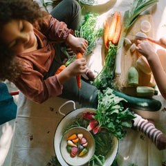 Kind spielt mit Veggies von Grapat - handbemaltes Holzgemüse liegt neben echtem Gemüse