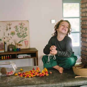 Kind spielt mit Warm Mandala Mix von Grapat - 81 Holzelemente in warmen orange-rot Tönen