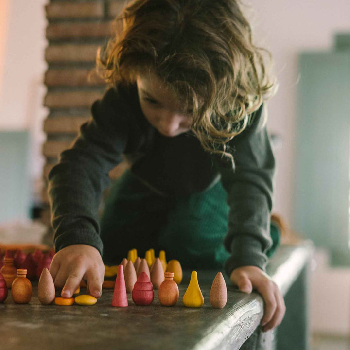 Kind spielt mit Warm Mandala Mix von Grapat - 81 Holzelemente in warmen orange-rot Tönen