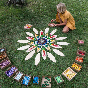 Kind legt Mandala von Grapat in der Wiese